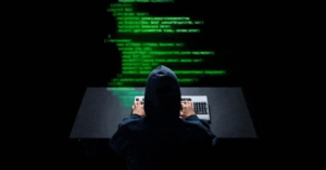 A hooded hacker typing code on a computer during a stealth cyberattack targeting Southeast Asian government systems