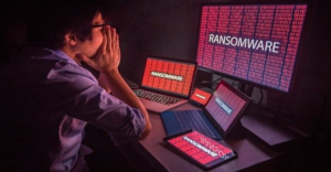 Multiple devices showing ransomware warnings while a person reacts, illustrating systems infected by Bearlyfy’s GenieLocker ransomware.