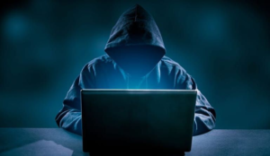 Hooded hacker using a laptop representing Russian-linked APT28 cyber espionage attacks targeting Ukrainian military systems.