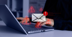 Hacker using laptop with warning signs showing phishing risks after McGraw Hill data breach exposure